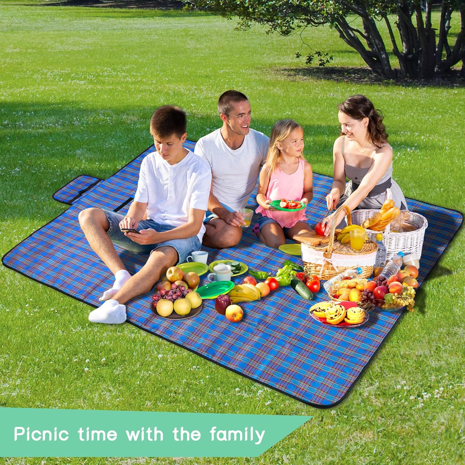 Family of four sitting on the blue tartan SOMIYAMI picnic mat in a park with baskets of food