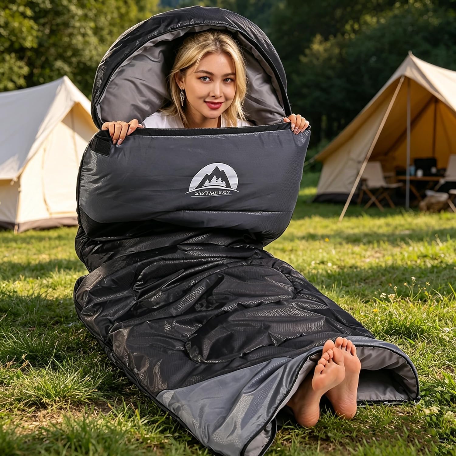 Camper resting on the SWTMERRY sleeping bag at a campsite with tents in the background