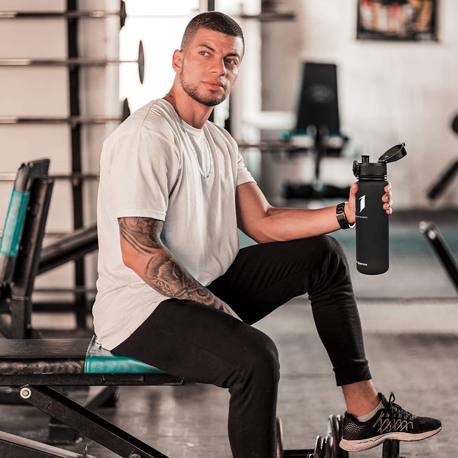 Man sitting on a weight bench in a gym holding a black Super Sparrow bottle