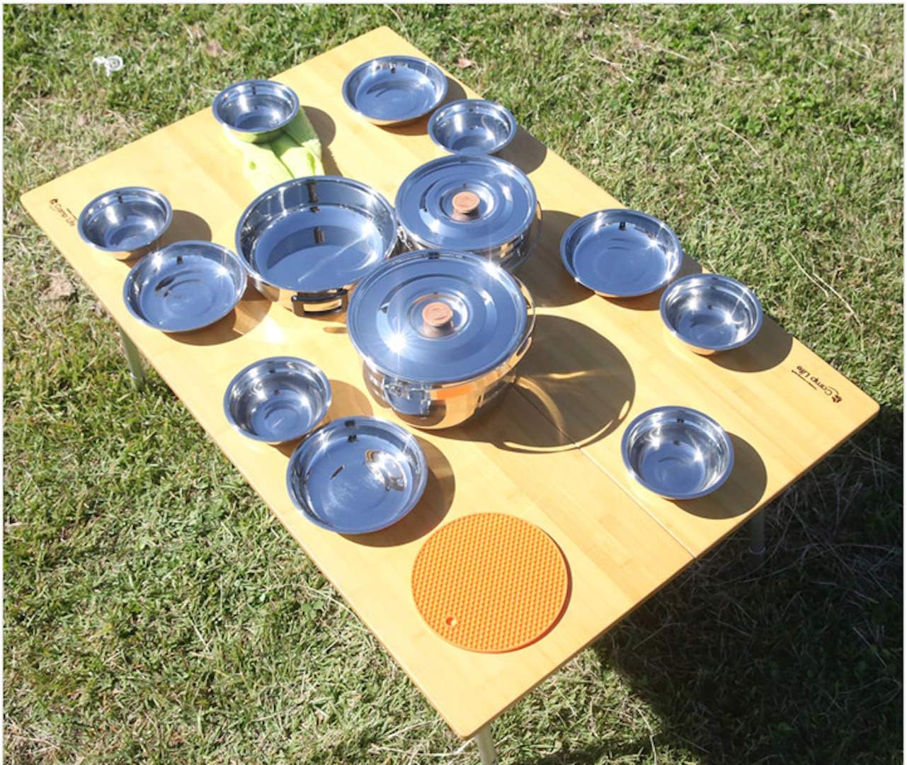 The full CAMPINGMOON set laid out on a wooden camp table showing the small bowls and plates beside the pots