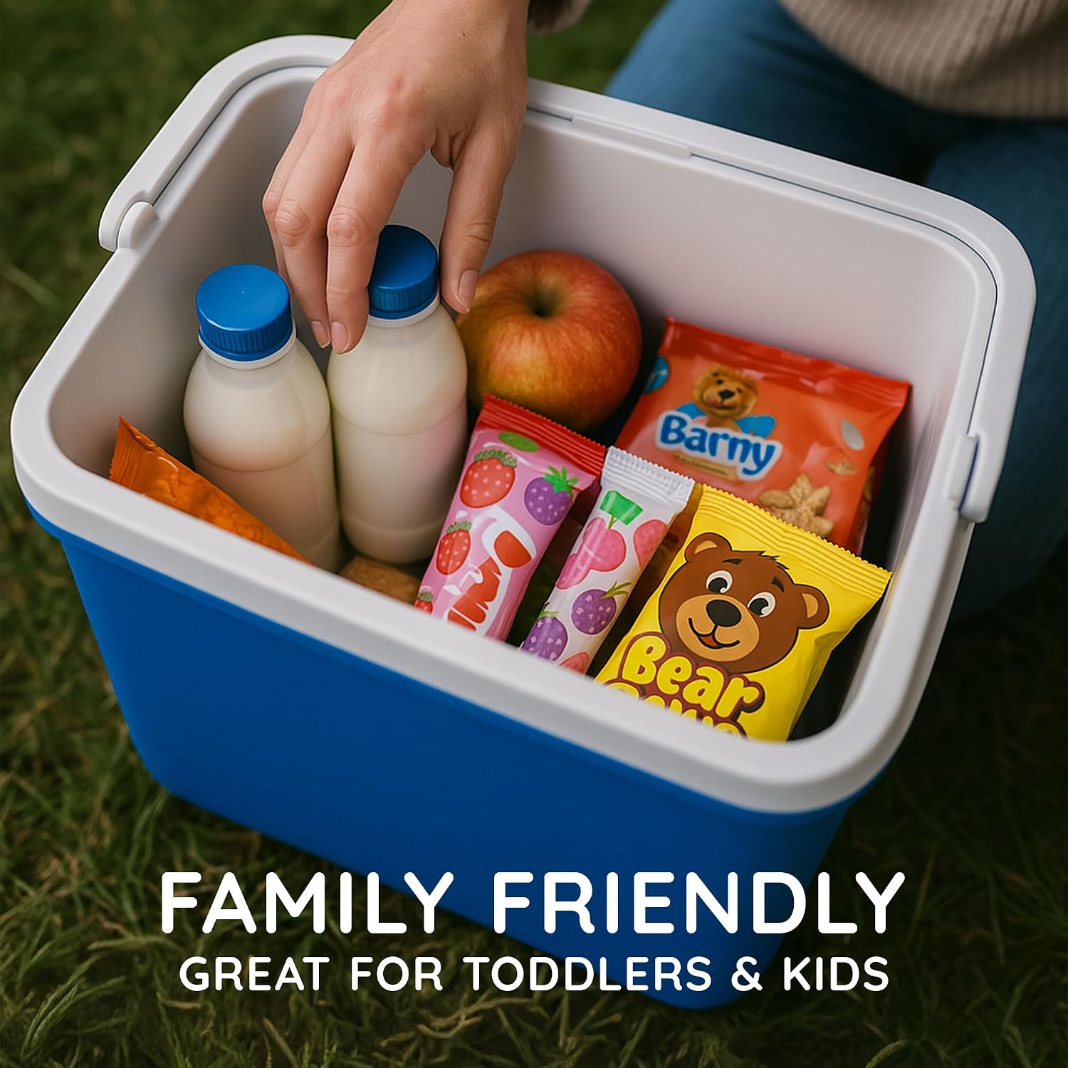 Open CUQOO cool box packed with milk bottles, an apple and children's snacks on grass