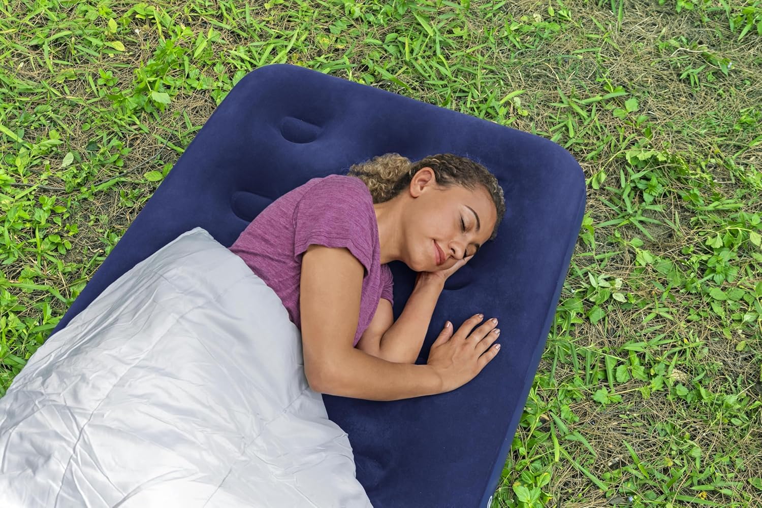 Overhead view of a woman sleeping on the Bestway single air bed with a grey sleeping bag on grass at a campsite