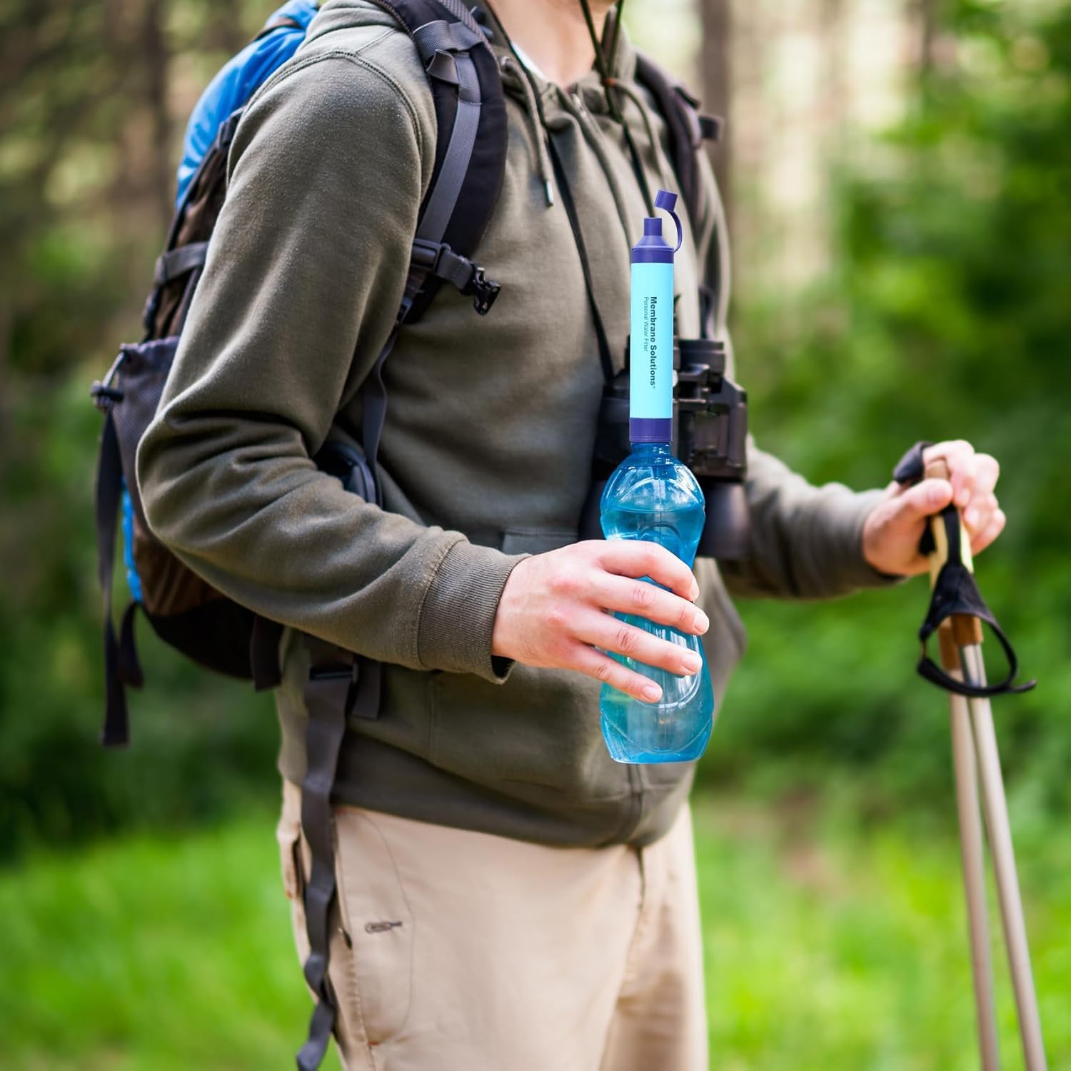 Hiker with the filter straw threaded onto a plastic drinks bottle on a woodland walk