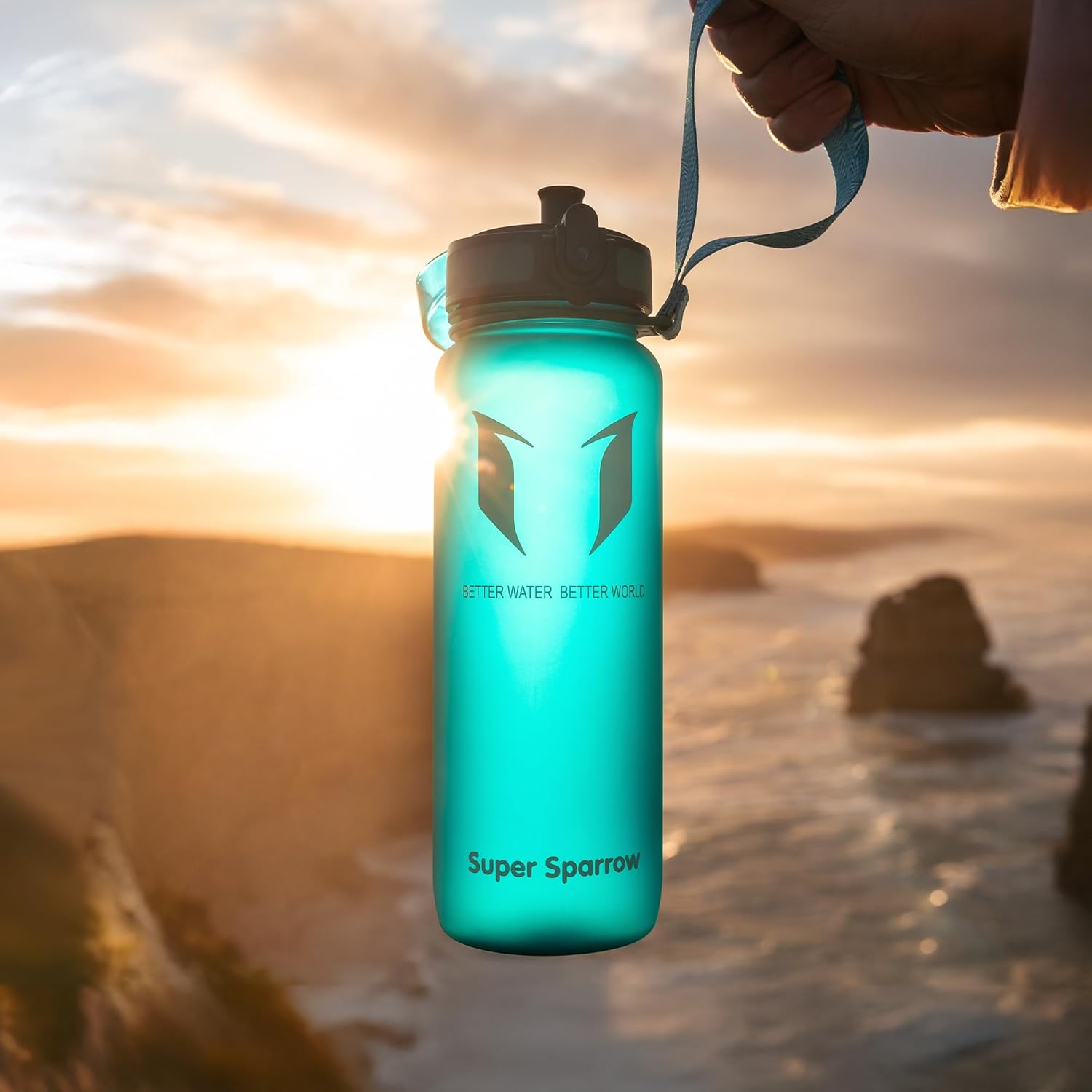 Turquoise Super Sparrow bottle held up by its carry strap against a coastal sunset