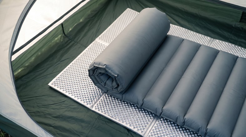 Foil foam mat layered under an inflatable sleeping pad to insulate from cold ground in a tent