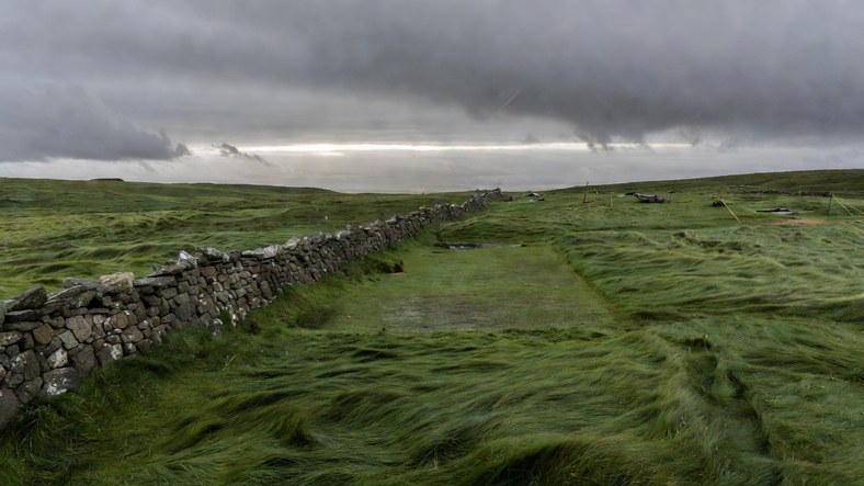 Sheltered tent pitch in the lee of a drystone wall on a windy UK hillside