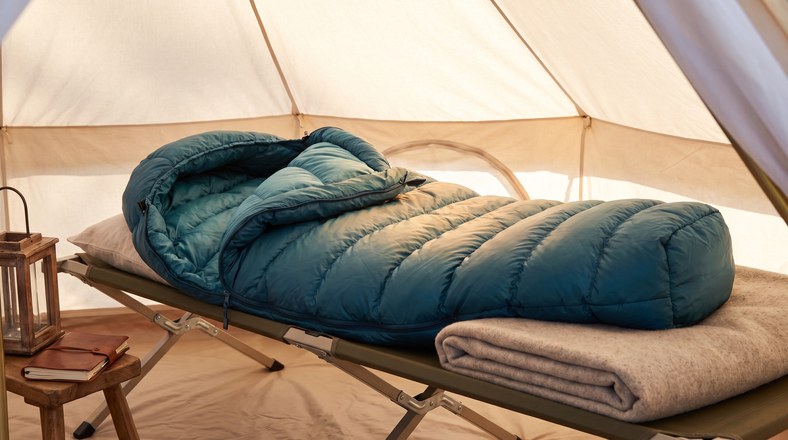 Lofted sleeping bag on a camp bed inside a tent for staying warm while camping in the UK