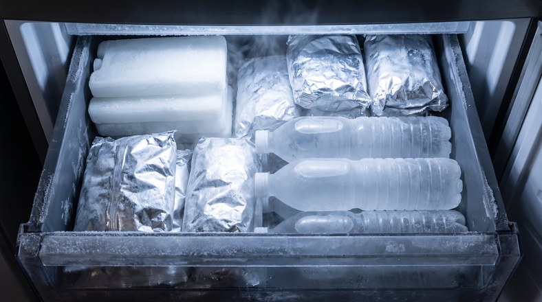 Freezer drawer of solid ice blocks and frozen bottles being pre-chilled the night before a camping trip