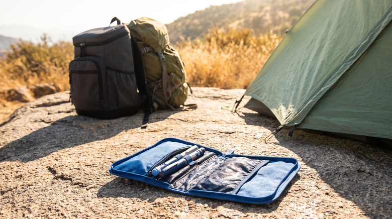 Insulin pens in an evaporative cooling wallet beside a cooler backpack for keeping insulin cool while wild camping in hot weather