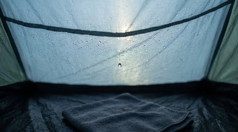 Condensation beaded on the inside of a tent flysheet at dawn, the usual cause of a tent seeming to leak