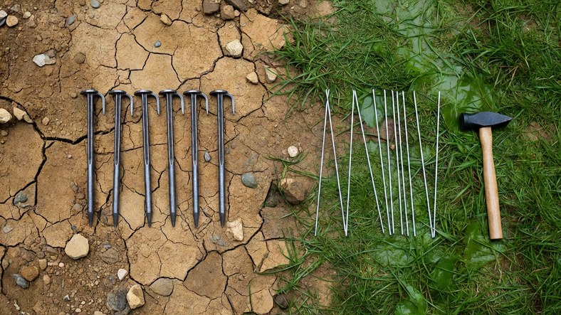 Heavy steel tent pegs for hard ground beside wire skewers for soft turf